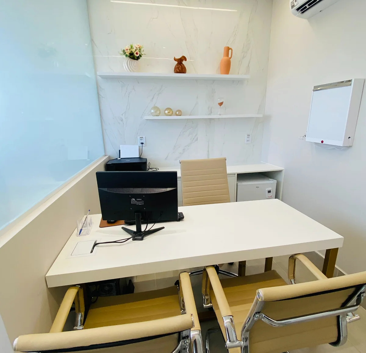 Um dos consultórios da unidade Prado do Instituto Hiraki, com mesa de atendimento e cadeiras.